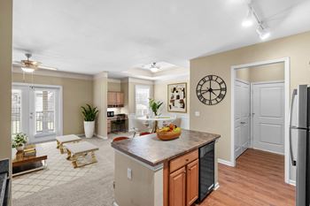 A kitchen with a refrigerator, a table, and a clock on the wall.